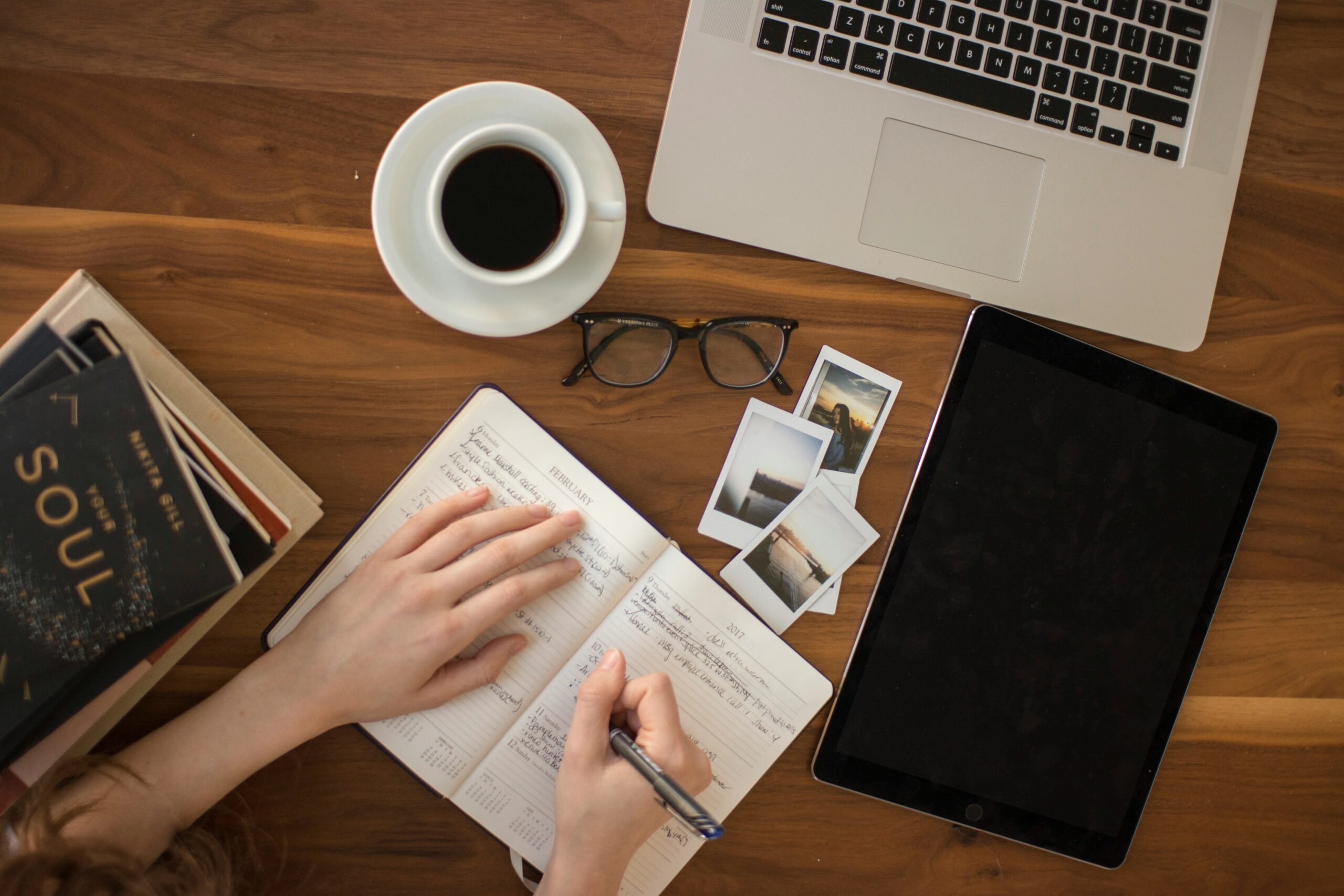 writing in notebook with glasses and coffee beside